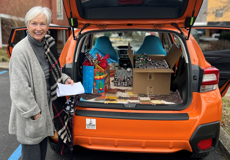 Woman next to vehicle filled with gifts.